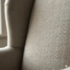 Close-up view of high-quality herringbone linen upholstery weave on a bespoke wingback chair.