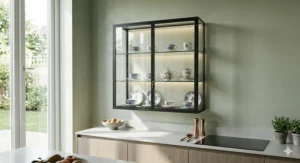 Wall-mounted glass display cabinet with integrated warm-white LED strips, used for storing fine bone china teacups in a modern kitchen.