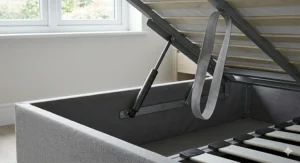 Close-up of an easy-access gas lift piston mechanism on a cheap ottoman storage bed.