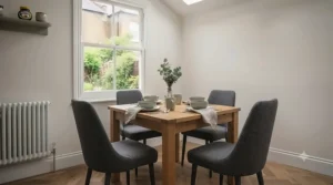 Compact four-seater small square dining table paired with upholstered chairs in a neutral-toned dining space.