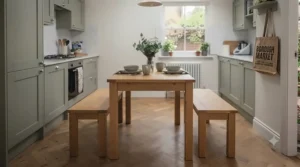 Space-saving small square dining table featuring two low-profile wooden benches tucked underneath to save floor space.