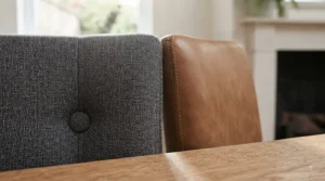 Compact leather dining chairs tucked neatly under a small wooden dining table in a British flat or apartment kitchen.