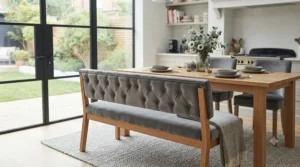 Grey velvet dining bench with a buttoned backrest positioned in a contemporary dining room.