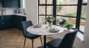 Open-plan kitchen-diner featuring a sleek marble effect dining table paired with velvet-fabric dining chairs.