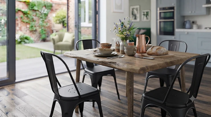 A modern open-plan British kitchen featuring sleek black metal dining chairs tucked around a solid oak dining table. metal dining chairs for kitchen