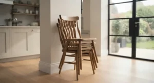 Lightweight stackable wooden kitchen chairs stored in the corner of a modern family kitchen.