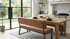 Tan faux leather dining bench with a high backrest paired with an industrial-style dining table.