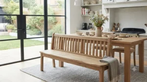 Traditional wooden kitchen dining bench with a vertical slat backrest in a country cottage interior.