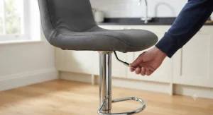 Height-adjustable grey leather swivel bar stool featuring a polished chrome gas-lift base and footrest.