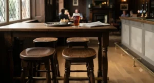 Traditional wooden backless bar stools arranged by a high Poseur table in a British gastropub