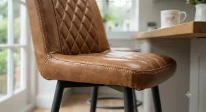 Close-up of premium brown genuine leather upholstery and contrast stitching on a luxury bar stool seat.